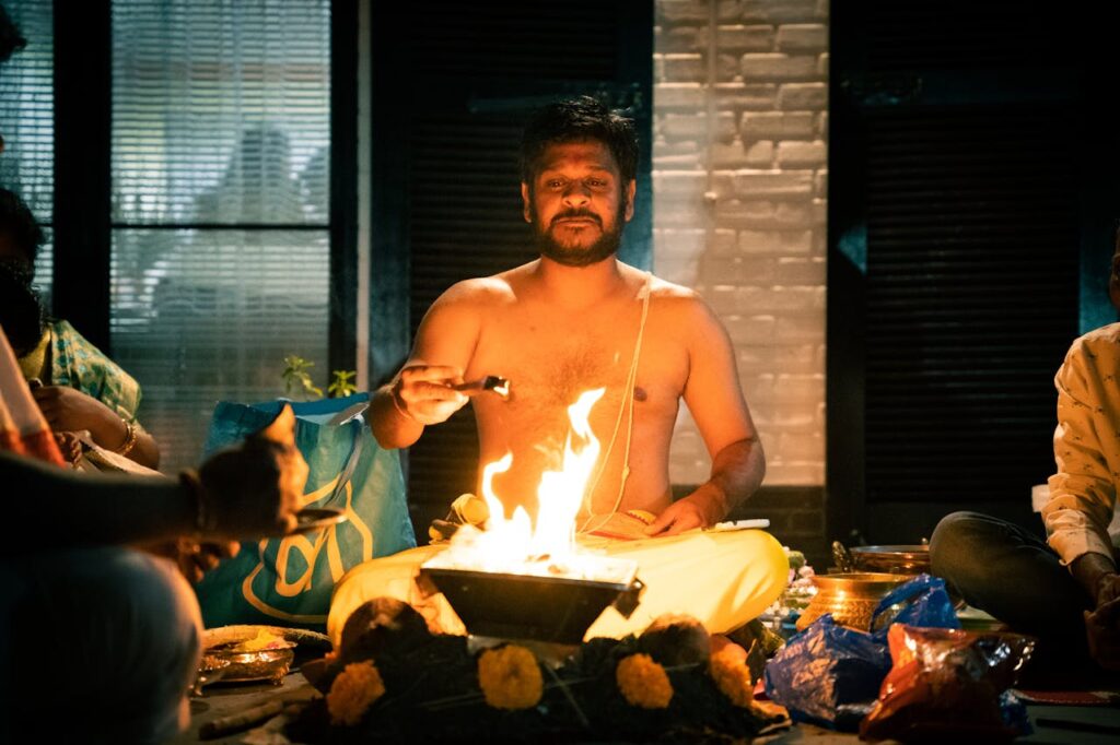 A Hindu priest performing a sacred fire ritual inside a dimly lit room, highlighting spiritual traditions.